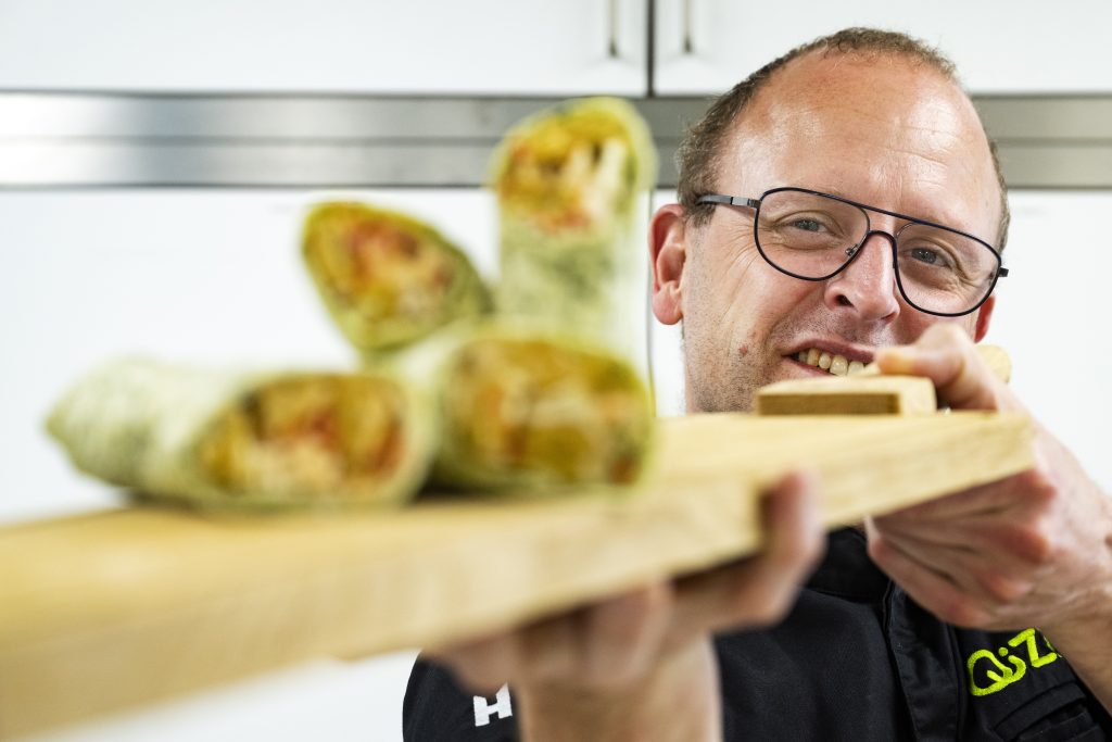 Rene van Vulpen met een plank met wraps, passen bij de Klantcase: Minifalafel Schouten in wraps QiZini